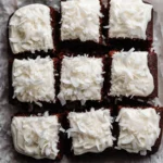 Healthy chocolate coconut snack cake topped with coconut flakes on a wooden table.