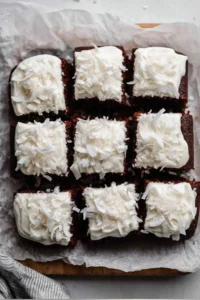 Healthy chocolate coconut snack cake topped with coconut flakes on a wooden table.