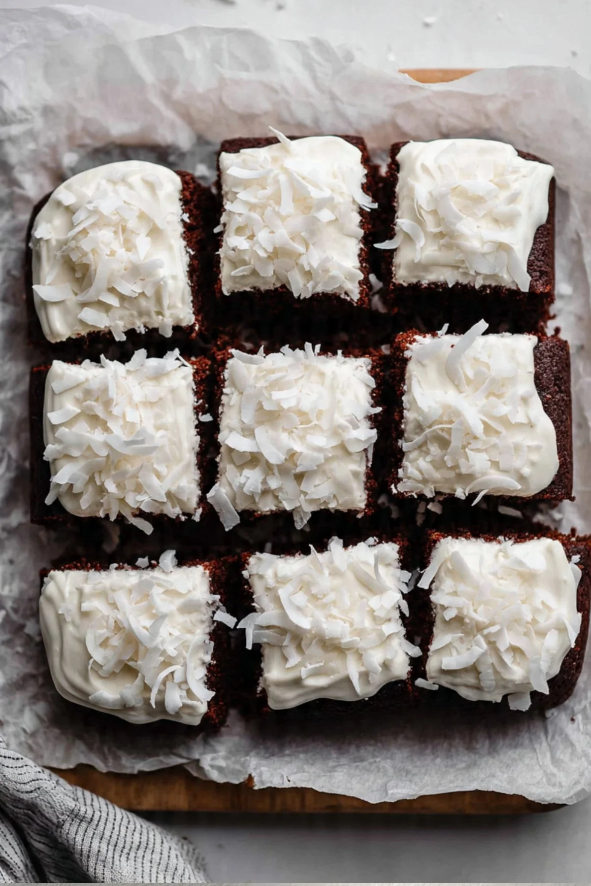 Healthy chocolate coconut snack cake topped with coconut flakes on a wooden table.