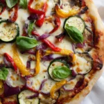 Delicious roasted veggie pizza topped with fresh vegetables and herbs.